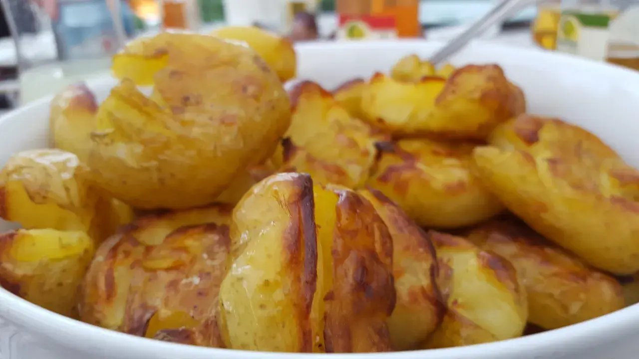 En skål med ugnsrostade potatisar, gyllene och krispiga. Perfekt för en middag med mycket potatis fibrer.