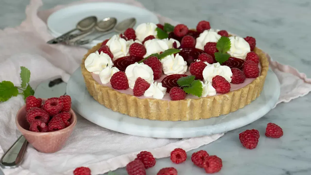 En vacker cheesecake hallon med vispgrädde och färska hallon. Perfekt för sommaren!