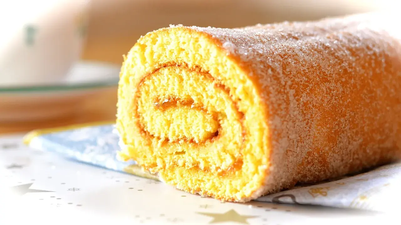 En saftig glutenfri rulltårta med socker strött över, perfekt för fikat.
