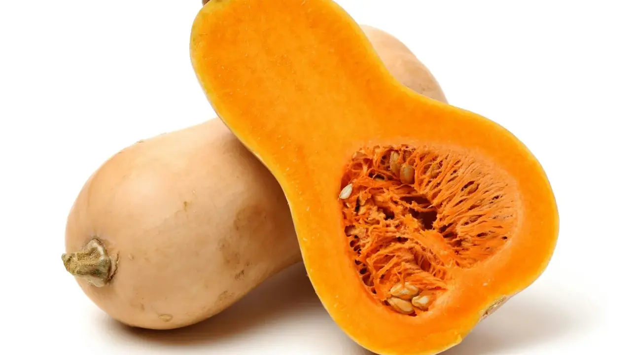 En hel och en halv butternutpumpa, med sitt orangea, fröfyllda inre. En riktigt nyttig och mångsidig grönsak.