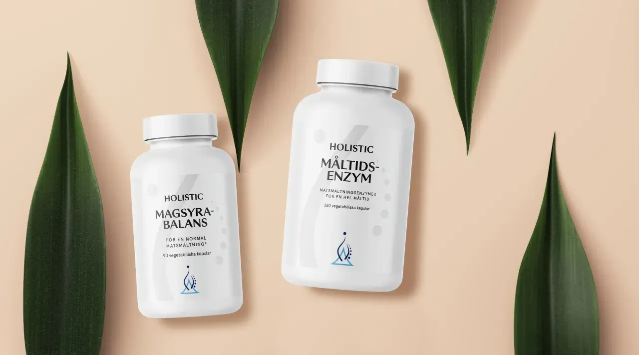 Två burkar med Holistic magsyra-balans och måltids-enzym, omgivna av gröna blad.