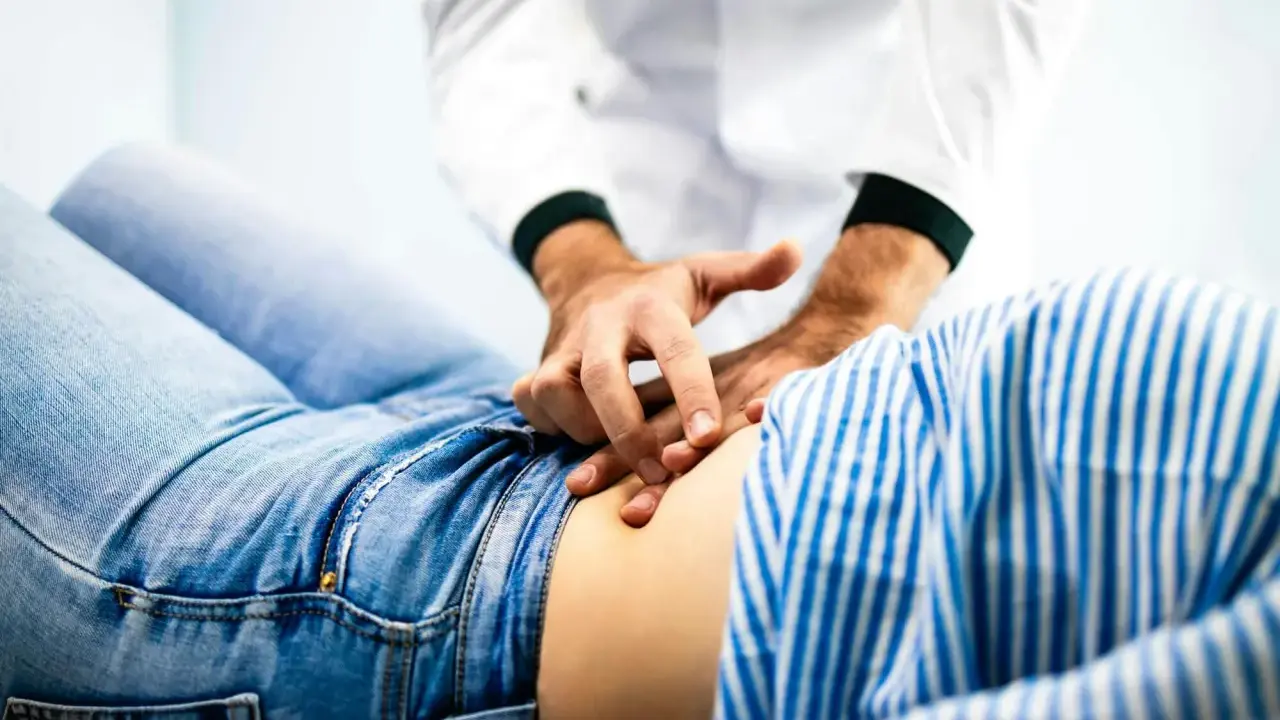 Läkare undersöker en patient som har ont i magen.