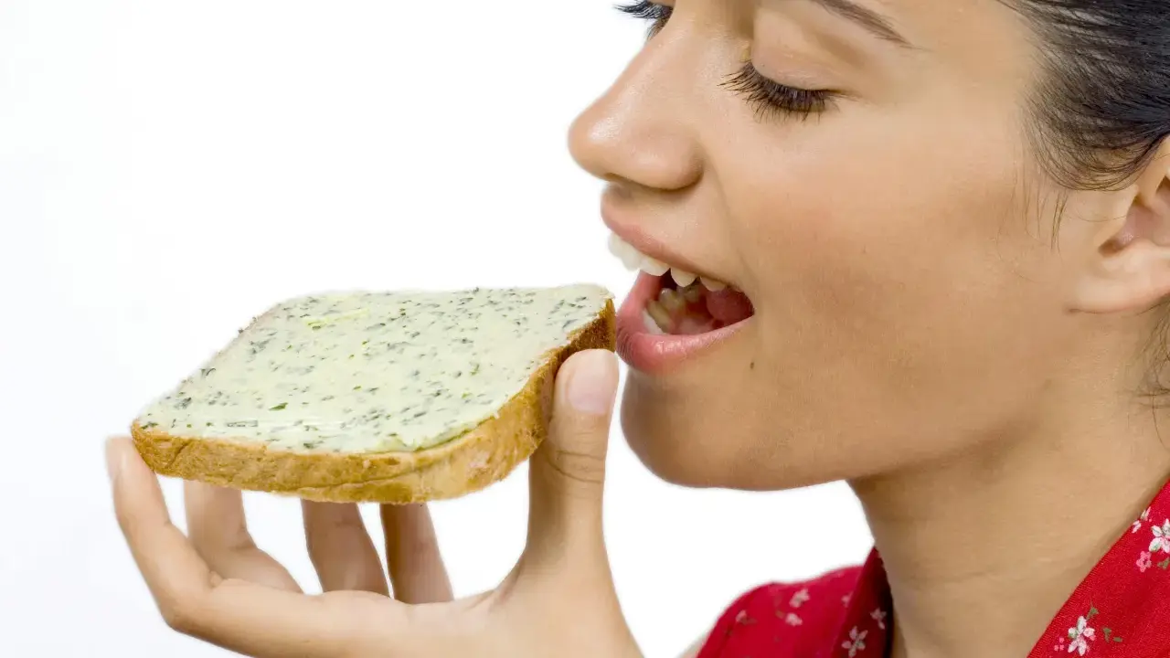 En kvinna med gluten mage njuter av en smörgås med örtsmör.
