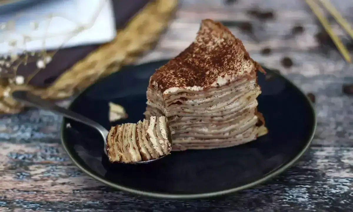 En skiva pannkakstårta med lager av grädde och kakao, perfekt för ett tiramisu recept.