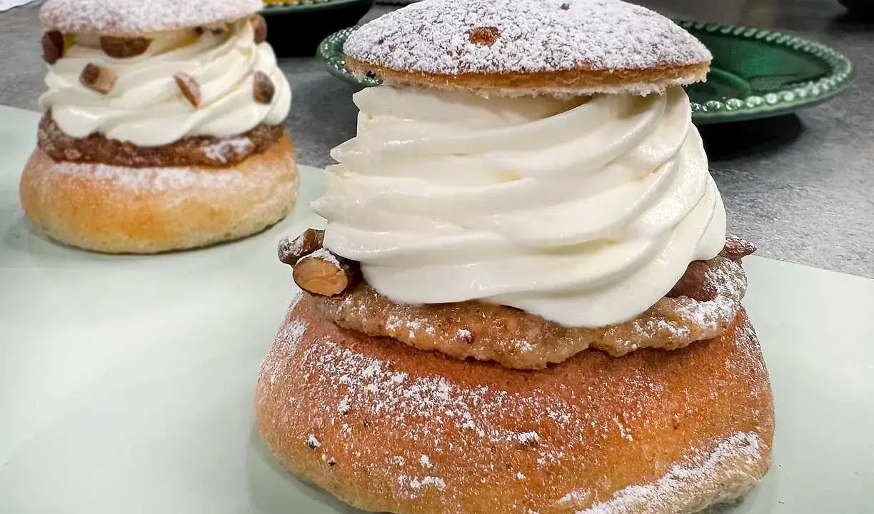 Två fluffiga semlor med rikligt med grädde och mandelmassa till semlor. Pudrade med florsocker och garnerade med mandelbitar.