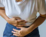 Person håller sig om magen, upplever smärta som kan vara relaterad till IBS och ont i ryggen.