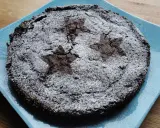En härlig glutenfri kladdkaka med stjärnmönster av florsocker på en blå tallrik.