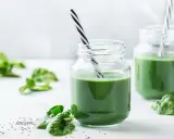 Två glas med grön smoothie, garnerade med färsk spenat och chiafrön. Tänk på spirulina biverkningar innan du dricker för mycket.