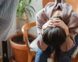 En person sitter med huvudet i händerna, kanske upplever svåra antabus biverkningar.
