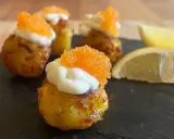 Små, krispiga tater tots toppade med gräddfil och orange rom. Citronklyftor ligger bredvid.