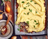 En ugnsbakad köttfärspaj med ett fluffigt potatismos som täcker hela ytan. Serveras med färska örter och peppar.