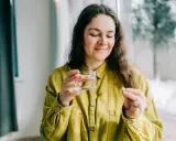 Kvinna med glas vatten och en tablett, funderar på magnesium tillskott biverkningar.