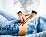 Läkare undersöker en patient som har ont i magen.