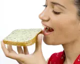 En kvinna med gluten mage njuter av en smörgås med örtsmör.