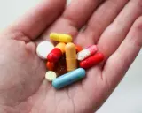 En hand håller flera färgglada piller och kapslar, inklusive en blå kapsel som kan vara en oxytocin tablett.
