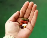 En hand håller flera kapslar i olika färger. Vissa funderar på losartan biverkningar.