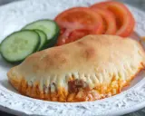 En gyllene pirog med ost och tomatsås, serverad med skivor av tomat och gurka. Ett perfekt piroger recept för en snabb och god måltid.