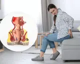 Kvinna med obehag som visar en modell av ändtarmen med hemorrojder och blod.