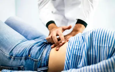 Läkare undersöker en patient som har ont i magen.