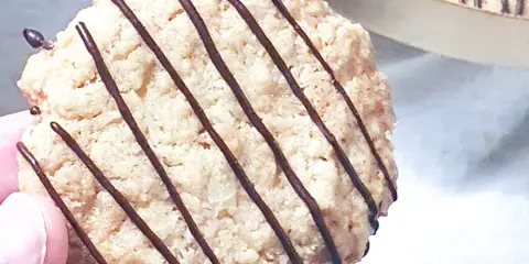 En hand håller en chokladglaserad havrekaka. Perfekt för ett enkelt havrekakor recept.
