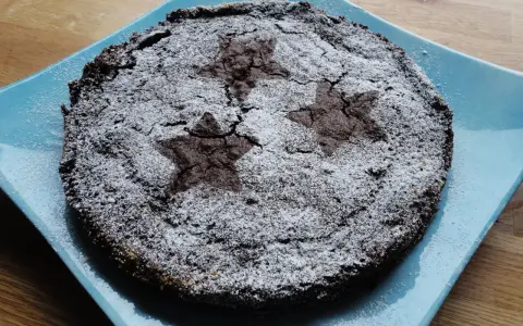 En härlig glutenfri kladdkaka med stjärnmönster av florsocker på en blå tallrik.