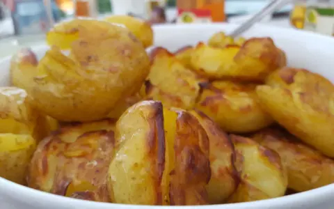 En skål med ugnsrostade potatisar, gyllene och krispiga. Perfekt för en middag med mycket potatis fibrer.