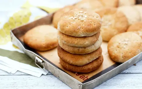 En stapel nybakade tekakor med havregryn på toppen, redo att avnjutas. Ett enkelt tekakor recept för hembakat bröd.