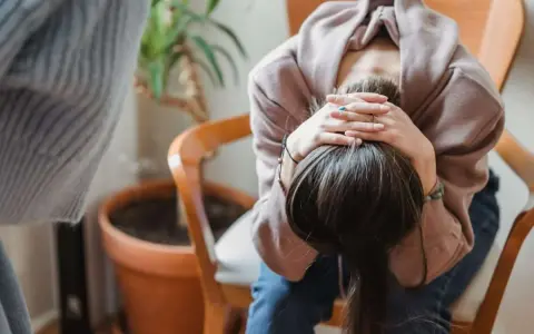 En person sitter med huvudet i händerna, kanske upplever svåra antabus biverkningar.