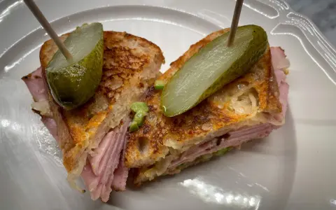 En saftig reuben sandwich med skinka, surkål och rostat bröd, toppad med dillgurka.