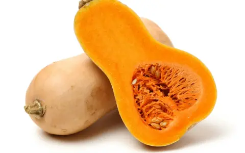 En hel och en halv butternutpumpa, med sitt orangea, fröfyllda inre. En riktigt nyttig och mångsidig grönsak.