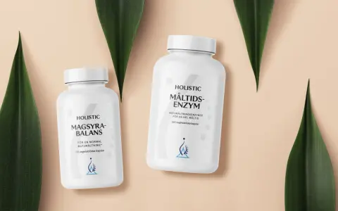 Två burkar med Holistic magsyra-balans och måltids-enzym, omgivna av gröna blad.