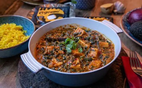En krämig palak paneer med gyllene ris. Vegoumi-förpackning syns i bakgrunden.