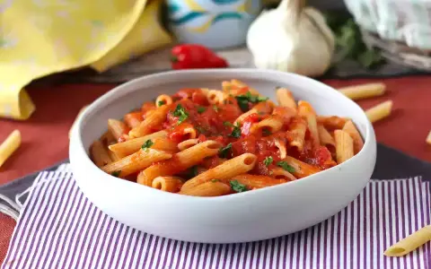 En skål med pasta arrabiata, toppad med färsk persilja. En klassisk italiensk rätt som värmer själen.