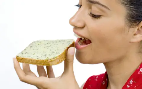 En kvinna med gluten mage njuter av en smörgås med örtsmör.