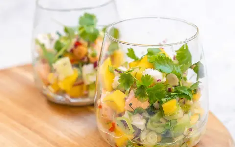Två glas med färgglad ceviche, perfekt för ett somrigt ceviche recept med mango, koriander och chili.