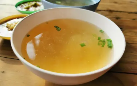 En skål med klar buljong, garnerad med gräslök. Perfekt som flytande kost vid tarmfickor.