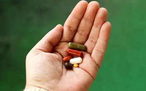 En hand håller flera kapslar i olika färger. Vissa funderar på losartan biverkningar.
