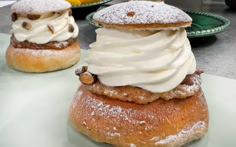 Två fluffiga semlor med rikligt med grädde och mandelmassa till semlor. Pudrade med florsocker och garnerade med mandelbitar.