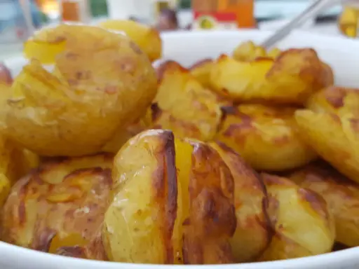 En skål med ugnsrostade potatisar, gyllene och krispiga. Perfekt för en middag med mycket potatis fibrer.