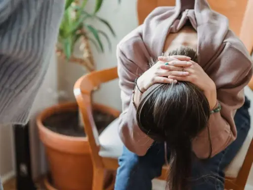 En person sitter med huvudet i händerna, kanske upplever svåra antabus biverkningar.