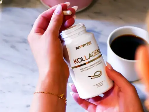 En hand håller en kapsel från en Better You Kollagen-burk. En kopp kaffe står bredvid. För en bättre du, natt biverkningar är minimala.