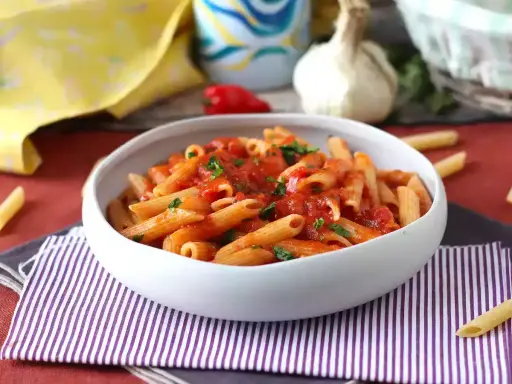 En skål med pasta arrabiata, toppad med färsk persilja. En klassisk italiensk rätt som värmer själen.