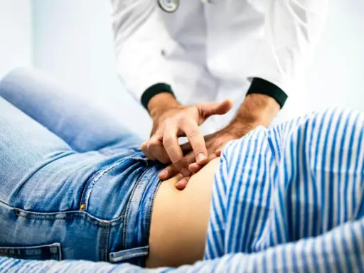 Läkare undersöker en patient som har ont i magen.