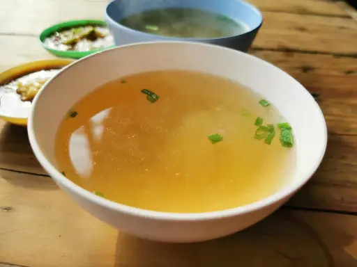 En skål med klar buljong, garnerad med gräslök. Perfekt som flytande kost vid tarmfickor.