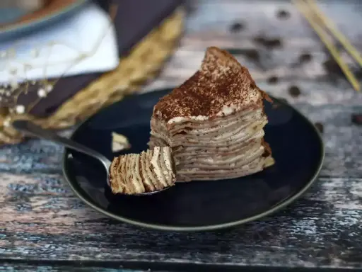 En skiva pannkakstårta med lager av grädde och kakao, perfekt för ett tiramisu recept.
