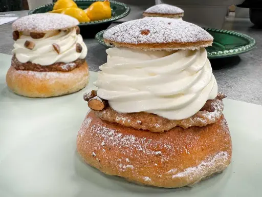 Två fluffiga semlor med rikligt med grädde och mandelmassa till semlor. Pudrade med florsocker och garnerade med mandelbitar.