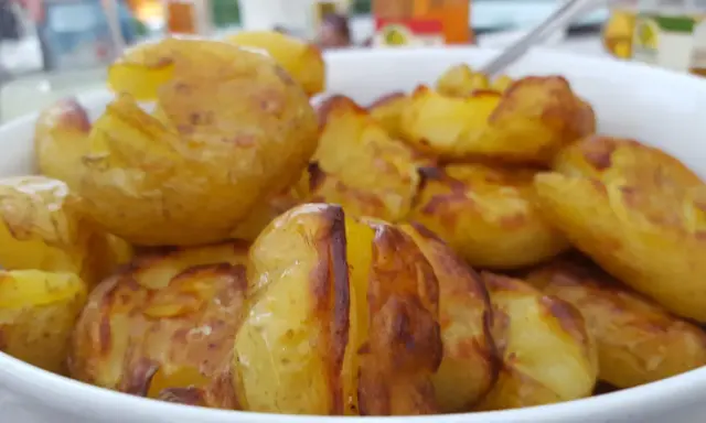 En skål med ugnsrostade potatisar, gyllene och krispiga. Perfekt för en middag med mycket potatis fibrer.