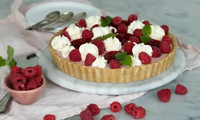 En vacker cheesecake hallon med vispgrädde och färska hallon. Perfekt för sommaren!