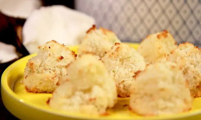 Små, gyllene kokostoppar på en gul tallrik, redo att avnjutas. Ett enkelt kokostoppar recept för hembakning.