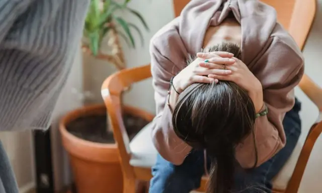 En person sitter med huvudet i händerna, kanske upplever svåra antabus biverkningar.